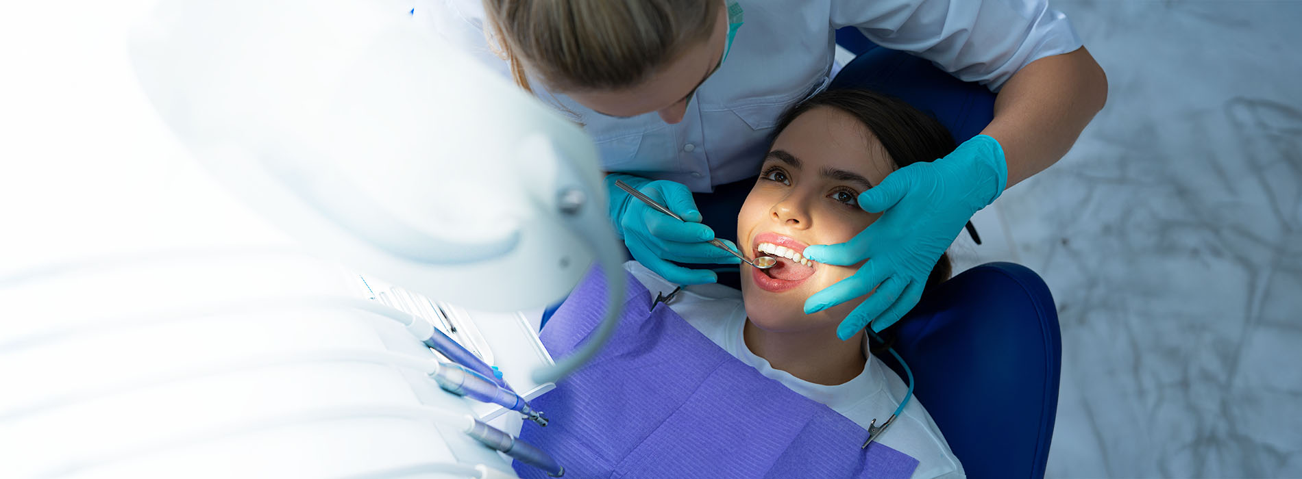 The image shows a dental hygienist assisting a patient during a dental appointment, with both individuals wearing appropriate personal protective equipment  PPE .
