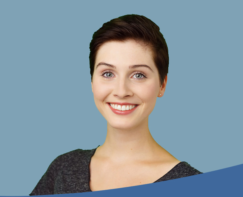 The image shows a woman with short hair smiling at the camera against a plain background.